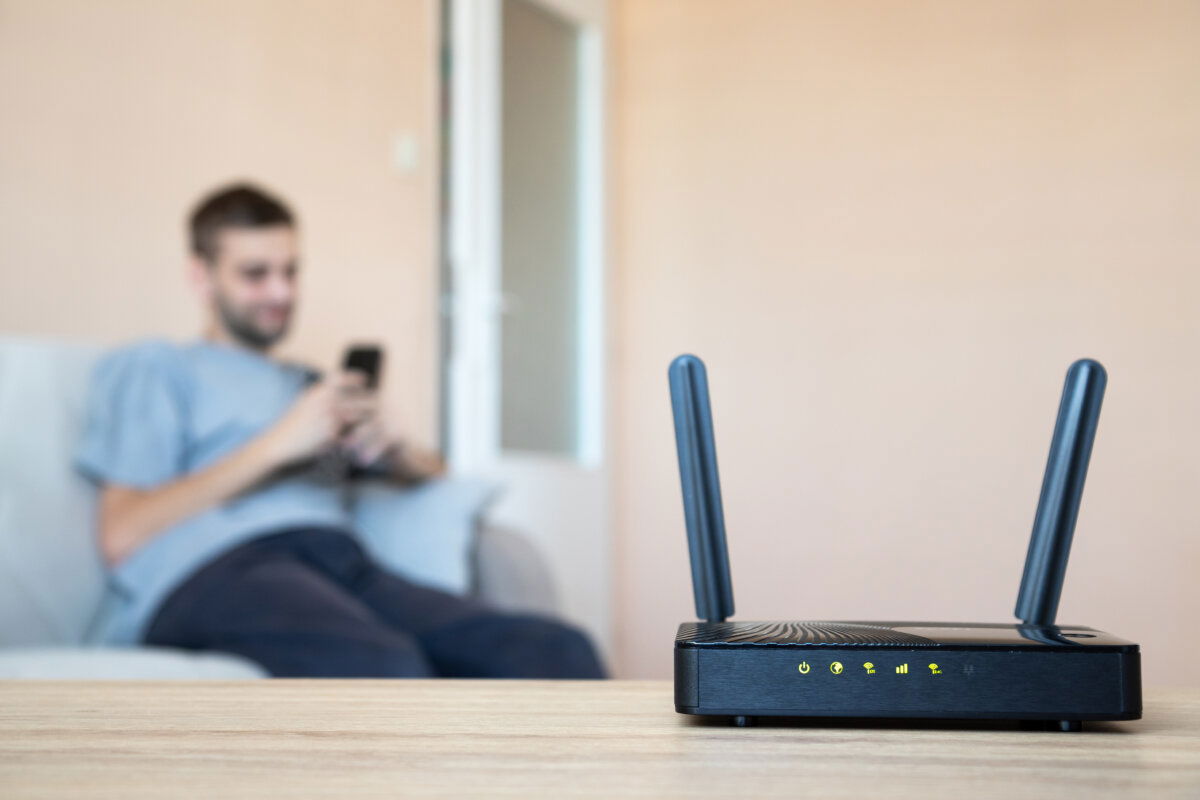 Private 5G network setup with a wireless router in focus and a user in the background on a smartphone – illustrating how 5G RedCap components enable simplified, cost-effective connectivity for residential, SME, and edge network applications.